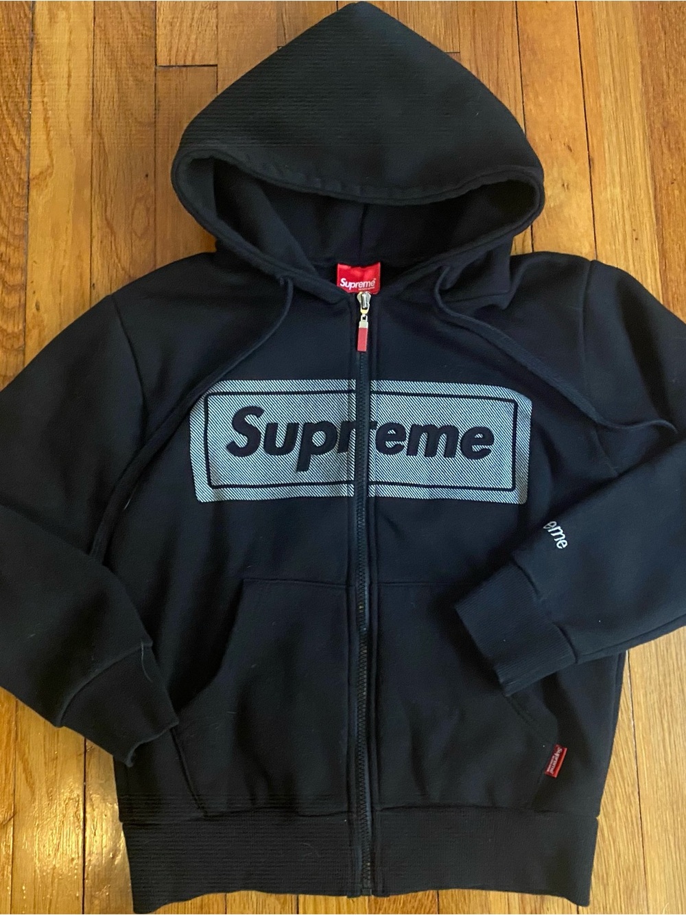 SUPREME Black Zip-Up Hoodie w/ Embossed Logo & Embroidered Sleeve.